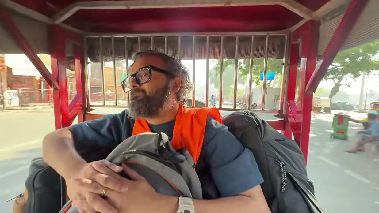 Meghnad riding in an auto-rickshaw, clutching his backpack