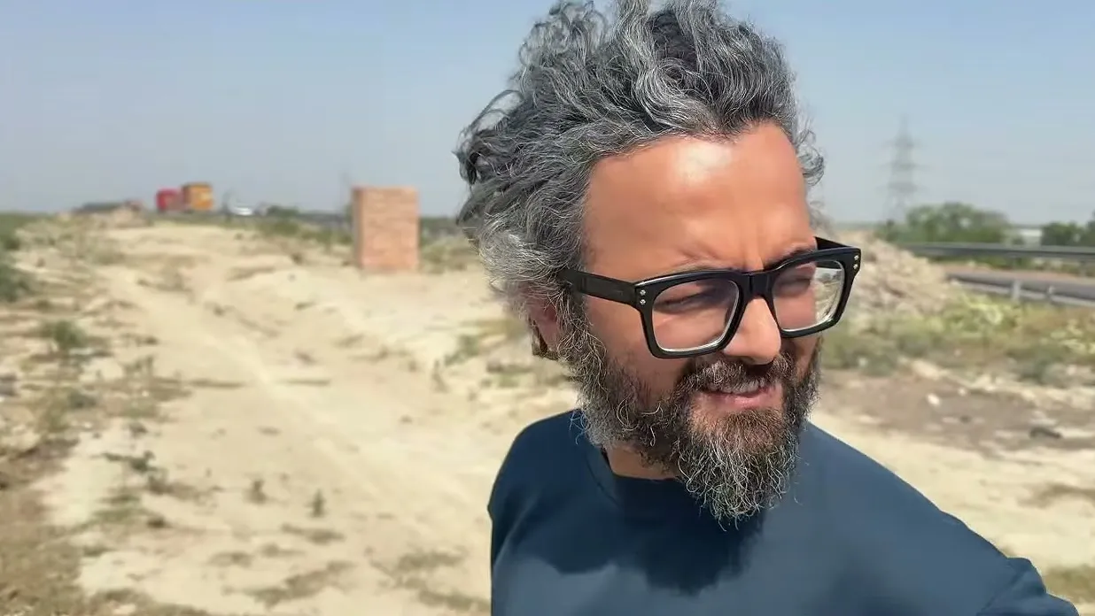 Meghnad grinning on a dusty roadside, hair blown by the wind