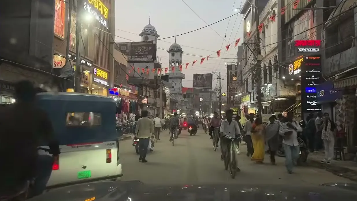 A busy market street at dusk, seen from the car